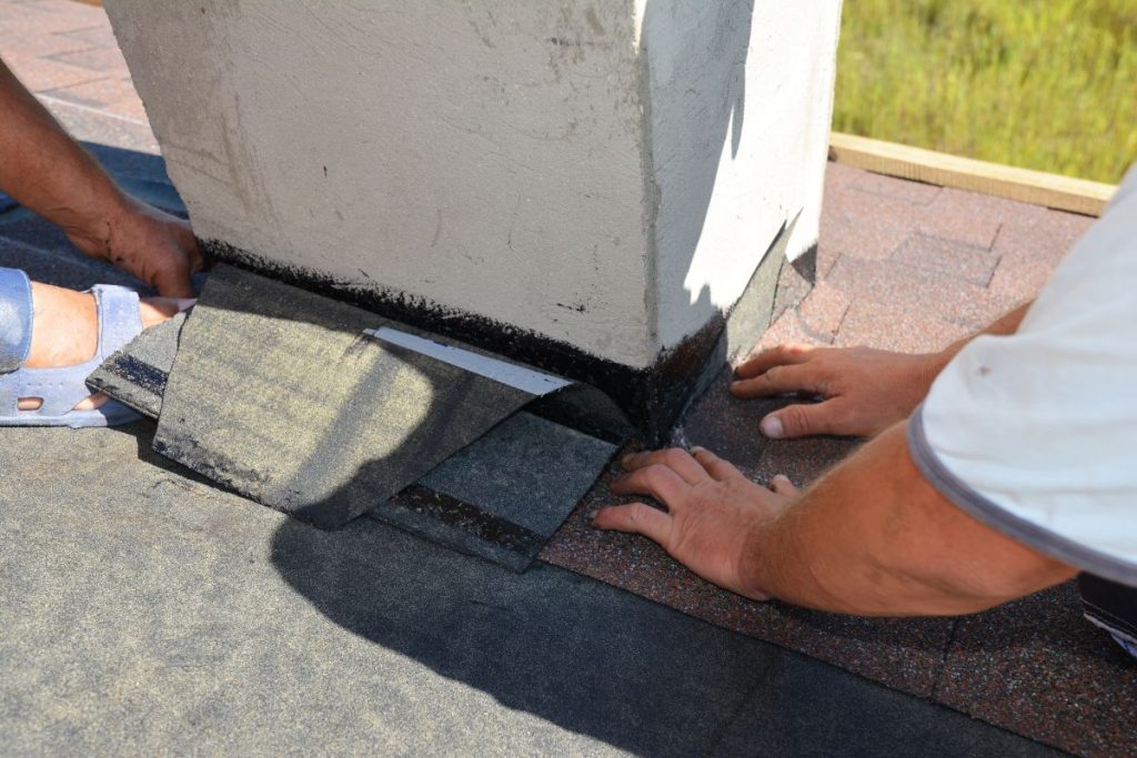A close-up on a roofing construction, installation of asphalt shingles on roof sheathing around a house chimney, Roseville, Minnesota